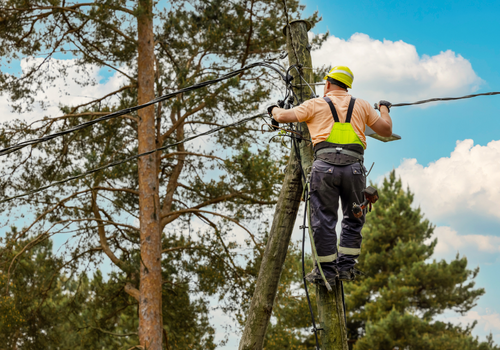 electrical lineman connecting wires high on electric pole. powerline maintenance and repair safety