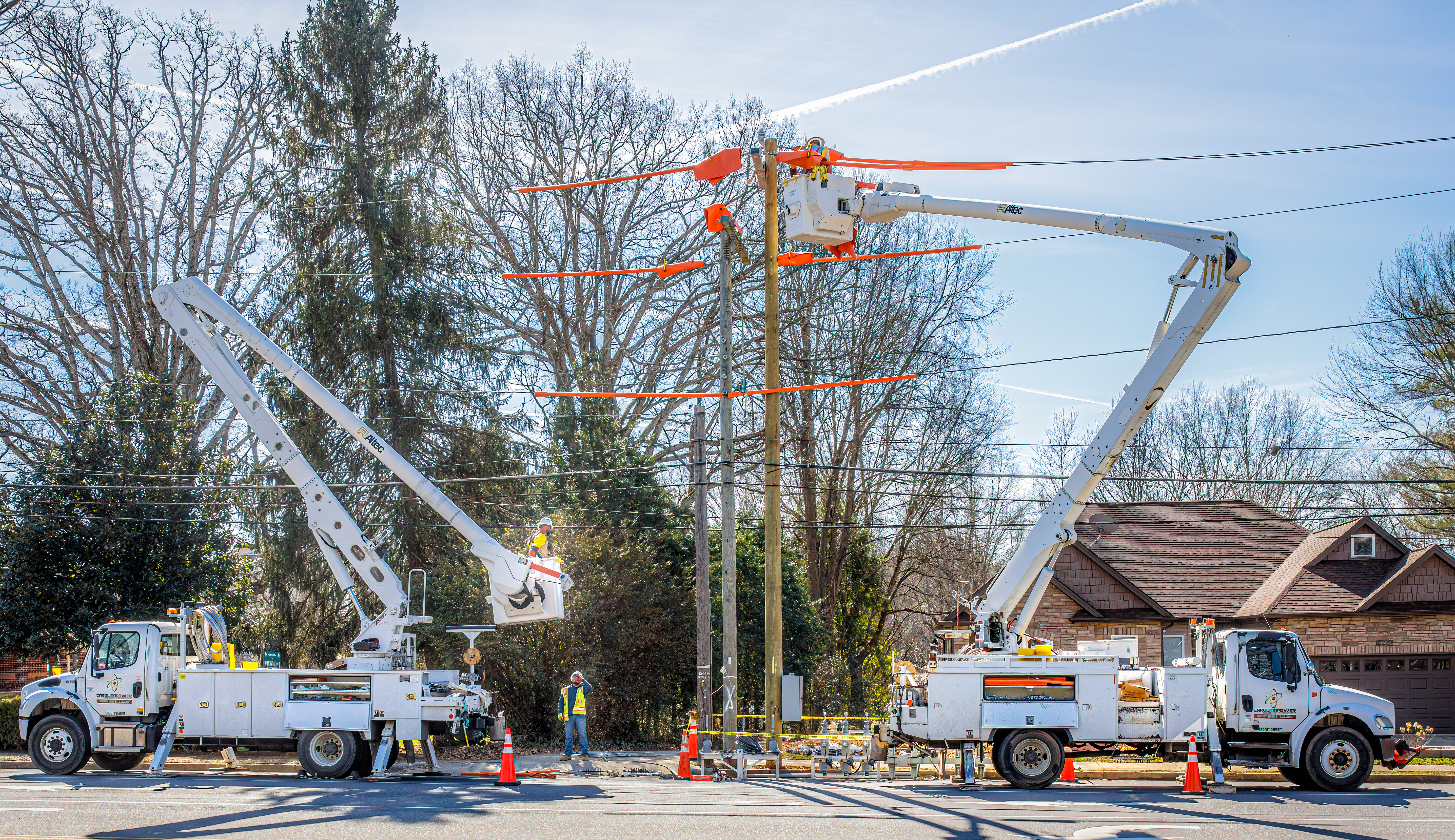 Hickory, NC, USA-14 Feb 2023: Utility workers with two bucket trucks repairing electrical lines.