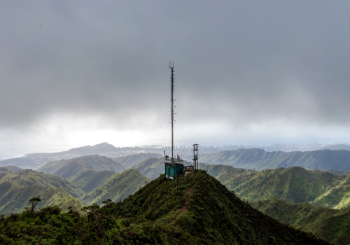 Stunning aerial drone view of a communications tower at the summit end of famous Wiliwilinui Ridge Hiking Trail near Honolulu on the island of Oahu, Hawaii. Coastline in the background & cloud cover.