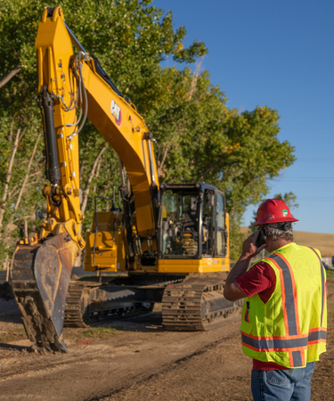 Construction worker on phone with equipment in the background