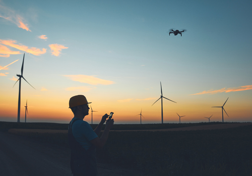 Engineer mechanic using drone for inspection in a windmill farm park.