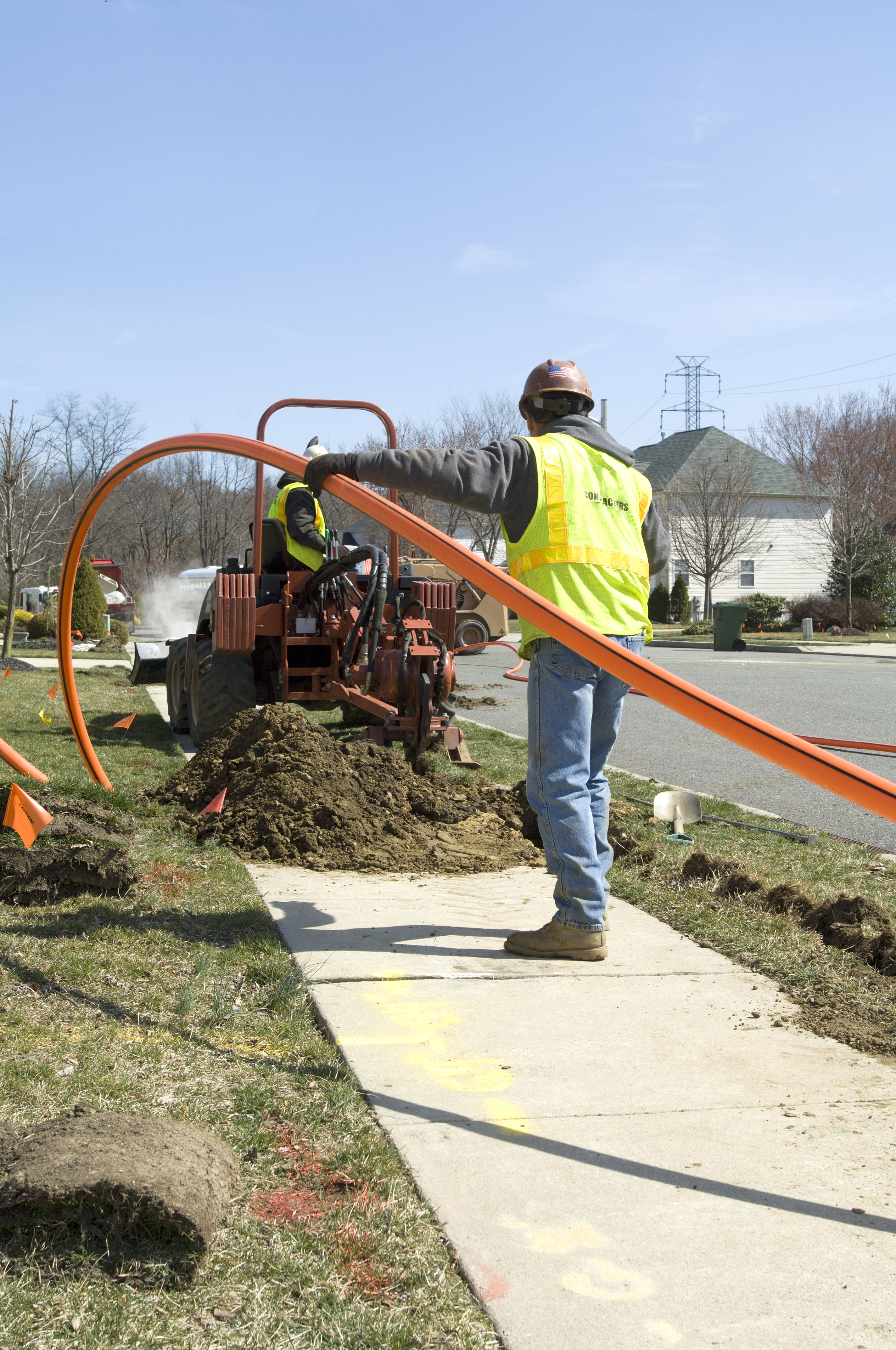 Two installers work together to install conduit for fiber optic cable.