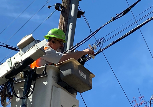 Utility worker in bucket truck installing fiber optic cable
