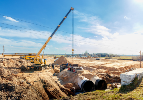 Connecting a trench drain to a concrete manhole structure at construction site. Concrete pile in formwork frame for construct stormwater and underground utilities, pump stations, sewers pipes.