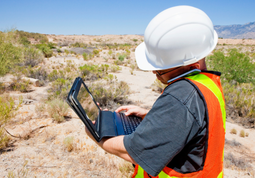 Construction worker on site using smart phone and tablet computer.