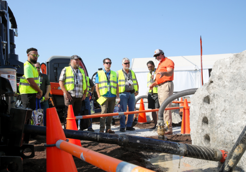 Crew of contractors gathering around horizontal directional drill in action with expert
