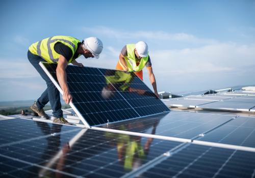 Team of two engineers installing solar panels on roof.