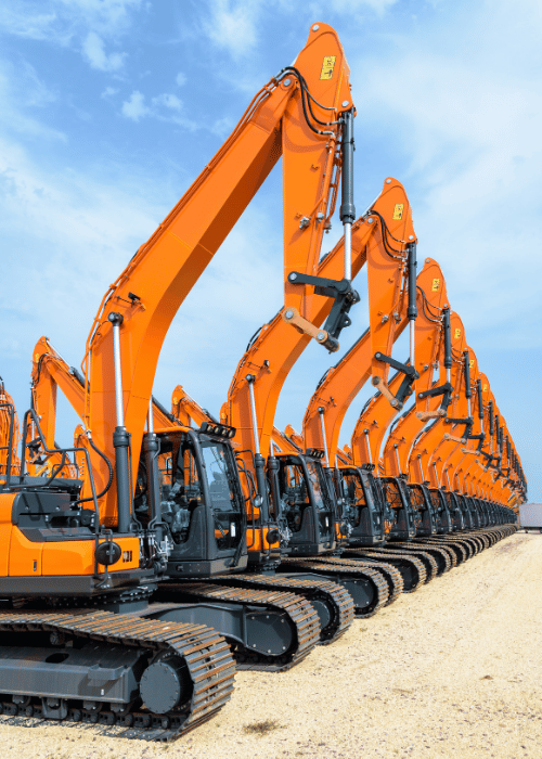 Tens of brand new orange excavators lined up in a row outdoors under a stormy sky.
