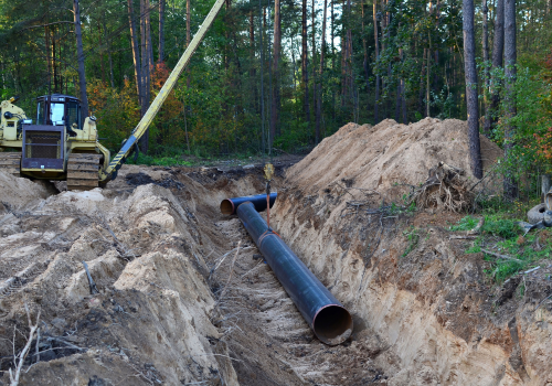 Natural gas pipeline construction work. A dug trench in the ground for the installation and installation of industrial gas and oil pipes. project. Crawler crane with side boom or pipelayer bulldozer