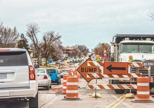 Trucks and road equipment on road with one lane blocked to horizon in urban area an cars navigation the construction