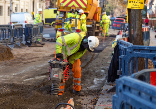 Man in yellow vest drilling the pavement in a London Street