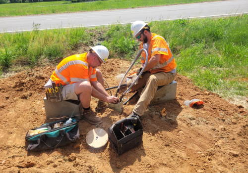 Construction workers on jobsite working on installing fiber optic cable underground